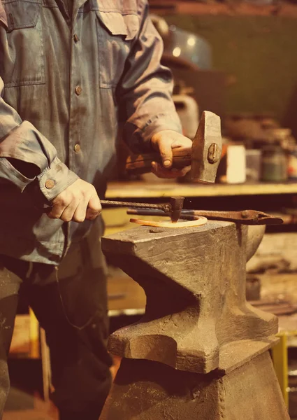 Maken van hoefijzer. Mannelijke werknemer met hamer maken van spijker gaten op hoefijzer. — Stockfoto