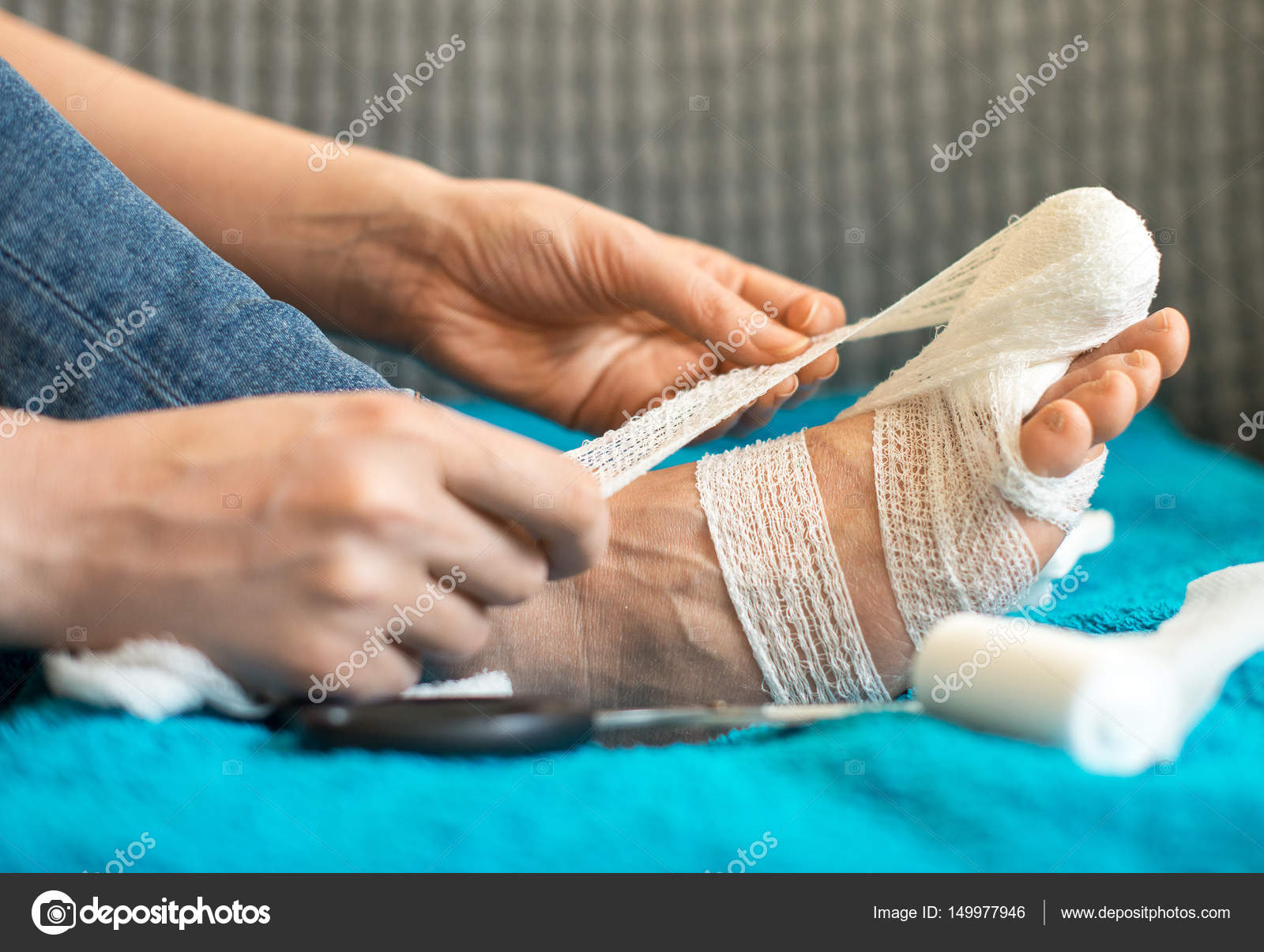 Woman bandaging her injured leg on sofa at home. Stock Photo by  ©mproduction 149977946