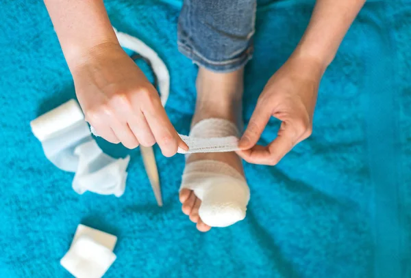 Mujer vendando su pierna lesionada en el sofá en casa . —  Fotos de Stock