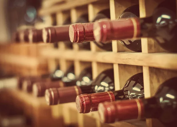 Red wine bottles stacked on wooden racks — Stock Photo, Image