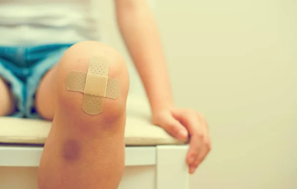 Child knee with an adhesive bandage and bruise. — Stock Photo, Image