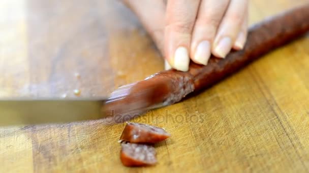 Femme avec couteau coupe saucisse fumée dans la cuisine . — Video