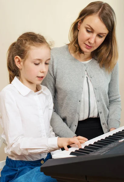 Femme enseignant à une petite fille à jouer du piano . — Photo
