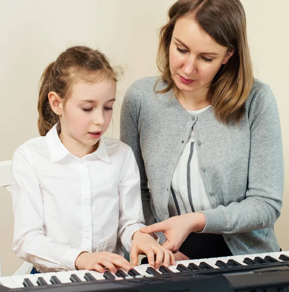 Vrouw onderwijs meisje om de piano te spelen. — Stockfoto
