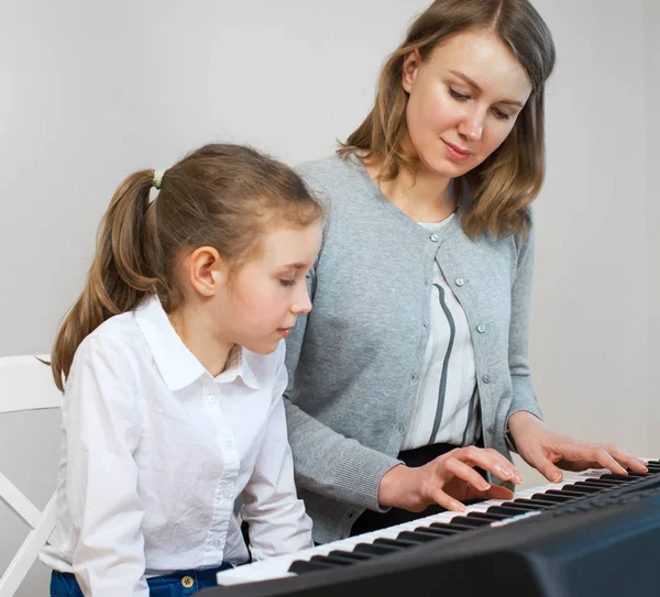 Femme enseignant à une petite fille à jouer du piano . — Photo