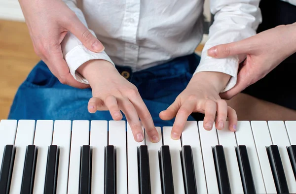 Жінка навчає маленьку дівчинку грати на піаніно . — стокове фото