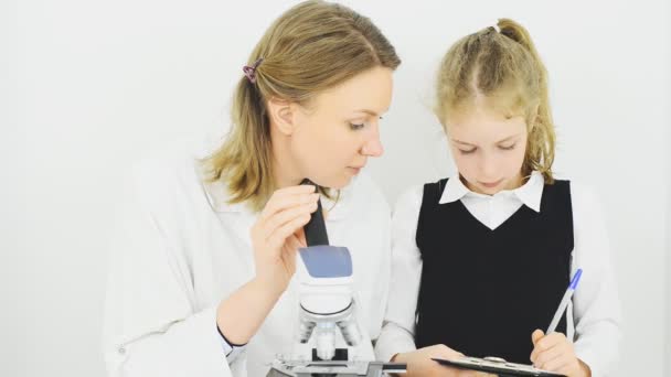 Mujer y niña usando microscopio en laboratorio . — Vídeos de Stock