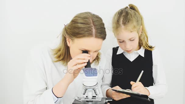 Mujer y niña usando microscopio en laboratorio . — Vídeos de Stock