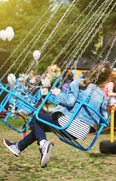 Little girl is riding a carousel in amusement park. — Stock Photo, Image