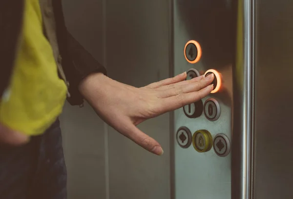 Asszony gomb megnyomásával gomb belsejében lift. — Stock Fotó