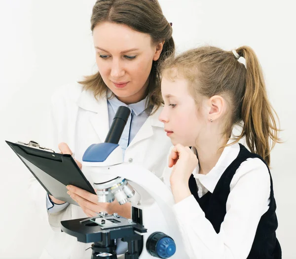 Kadın ve küçük kızı laboratuarda mikroskop kullanarak. — Stok fotoğraf