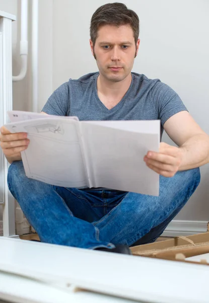 Человек читает инструкции по сборке мебели . — стоковое фото