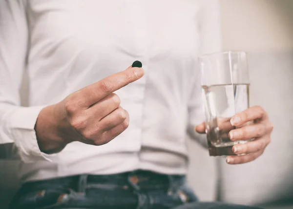 Vrouw hand met actieve kool pillen. — Stockfoto