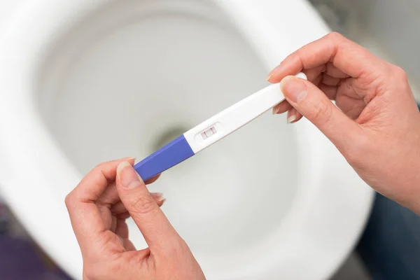Woman holding positive pregnancy test. — Stockfoto