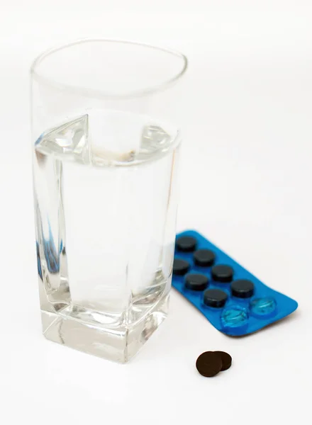 Activated carbon pills and glass of water. — Stock Photo, Image