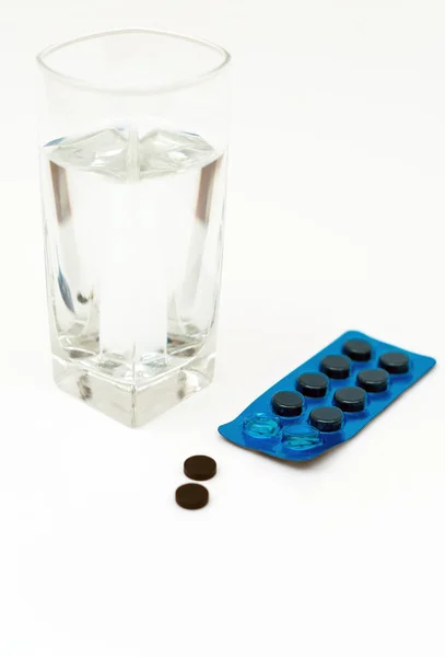 Pastillas de carbón activadas y vaso de agua . — Foto de Stock