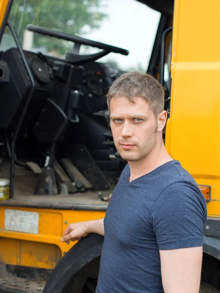Чоловік вантажівка стоїть біля своєї жовтої вантажівки . — стокове фото