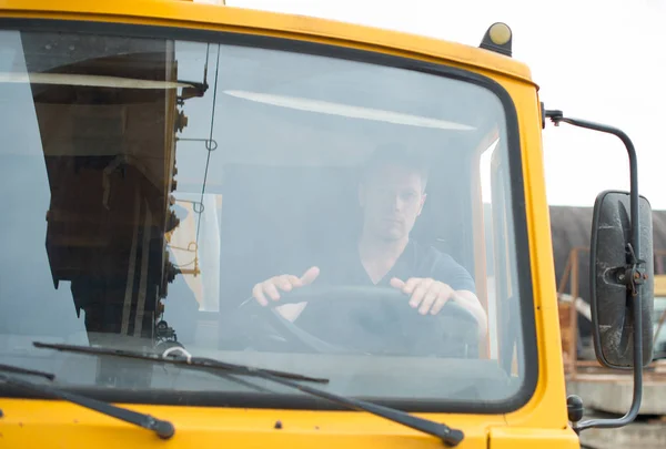 Maschio camionista in cabina del suo camion giallo . — Foto Stock