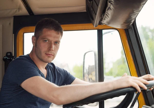 Mannelijke trucker in de cabine van zijn gele vrachtwagen. — Stockfoto