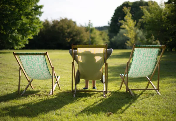 Chaise のラウンジで太陽を楽しんでいる女性。後ろから. — ストック写真