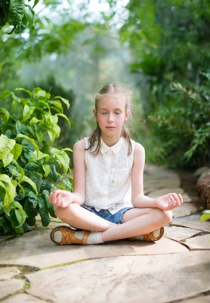 Menina bonito meditando no jardim . — Fotografia de Stock