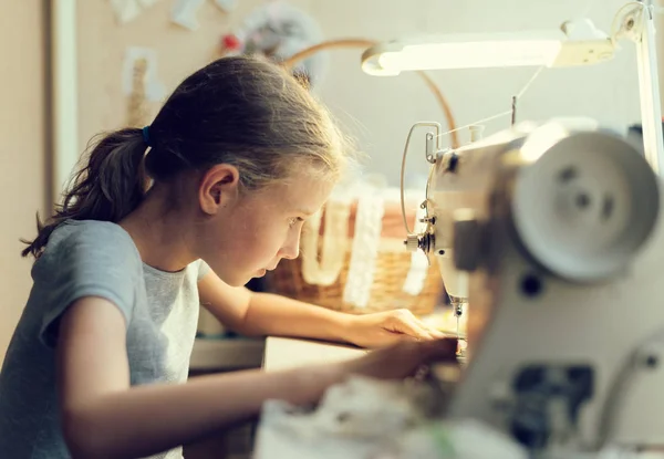 Kleines Mädchen arbeitet zu Hause an Nähmaschine. — Stockfoto