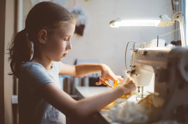 Petite fille travaillant sur la machine à coudre à la maison . — Photo