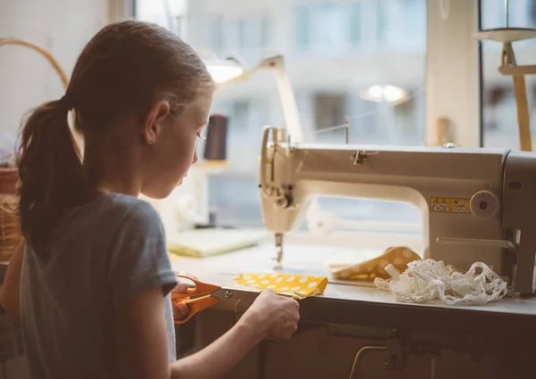 Kleines Mädchen arbeitet zu Hause an Nähmaschine. — Stockfoto