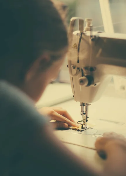 Petite fille qui travaille sur une machine à coudre à la maison. Vue rapprochée . — Photo