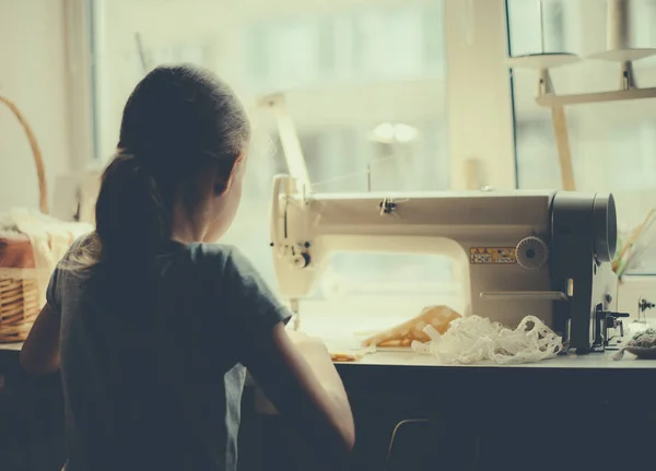 Little girl working on sewing machine at home. — Stock Photo, Image