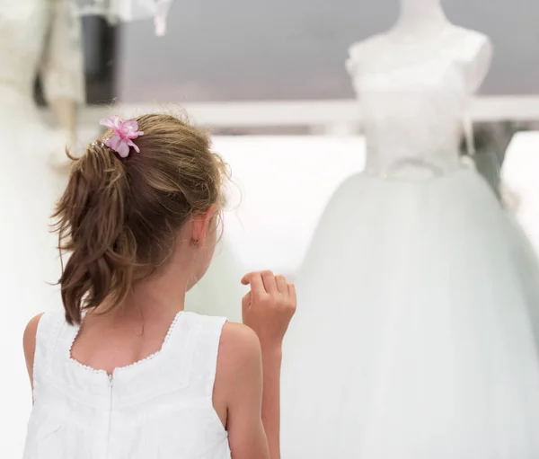 Menina olhando vitrine com vestidos de noiva . — Fotografia de Stock