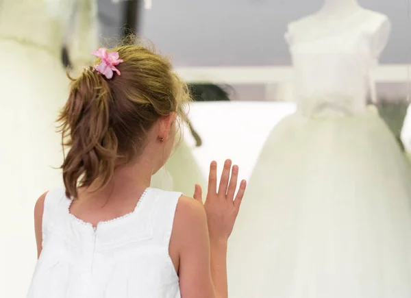 Menina olhando vitrine com vestidos de noiva . — Fotografia de Stock