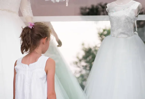 Menina olhando vitrine com vestidos de noiva . — Fotografia de Stock
