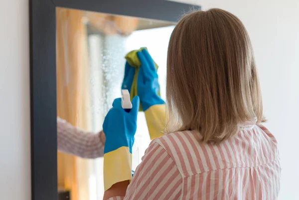 Limpeza da casa. Mulher está limpando espelho no quarto . — Fotografia de Stock