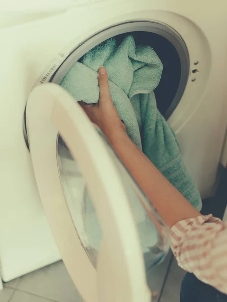 Pulizia della casa. Donna che mette l'asciugamano in lavatrice . — Foto Stock