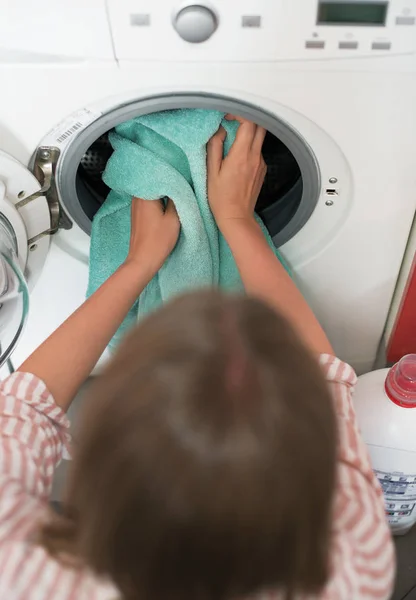 Уборка дома. Женщина кладет полотенце в стиральную машину . — стоковое фото