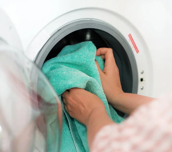 Pulizia della casa. Donna che mette l'asciugamano in lavatrice . — Foto Stock