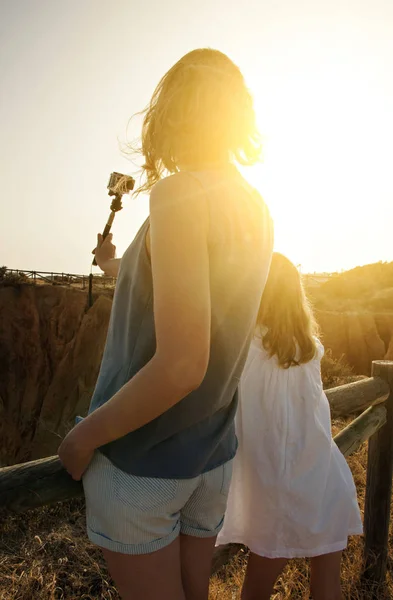 Vrouw en haar dochter doen selfie bij zonsondergang. — Stockfoto