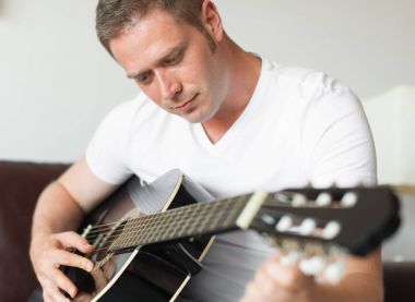 Yakışıklı adam evde bir gitar tuning.