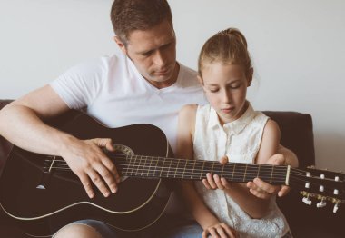 Baba kızı gitar çalmayı öğretir.