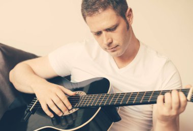Yakışıklı adam evde gitar çalıyor..