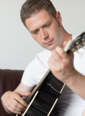 Yakışıklı adam evde gitar çalıyor..