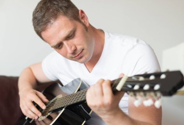 Yakışıklı adam evde gitar çalıyor..