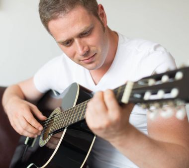 Yakışıklı adam evde gitar çalıyor..
