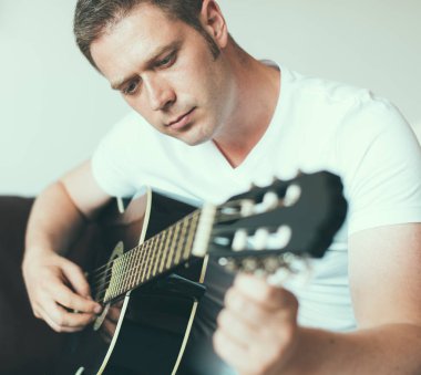 Yakışıklı adam evde bir gitar tuning.