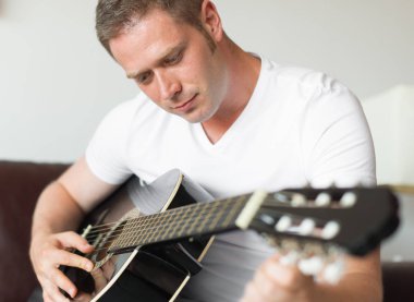 Yakışıklı adam evde bir gitar tuning.