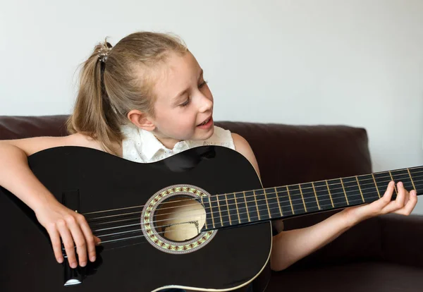 Lilla flickan lär sig att spela gitarr. — Stockfoto