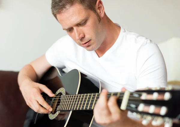 Hombre guapo tocando la guitarra en casa. — Foto de Stock