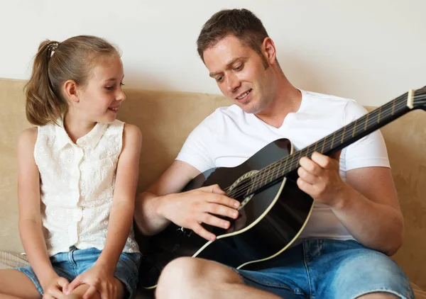 Baba kızı için gitar çalıyor.