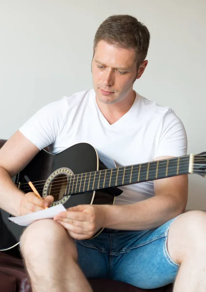 Handsome man compose a song on the guitar. — Stock Photo, Image